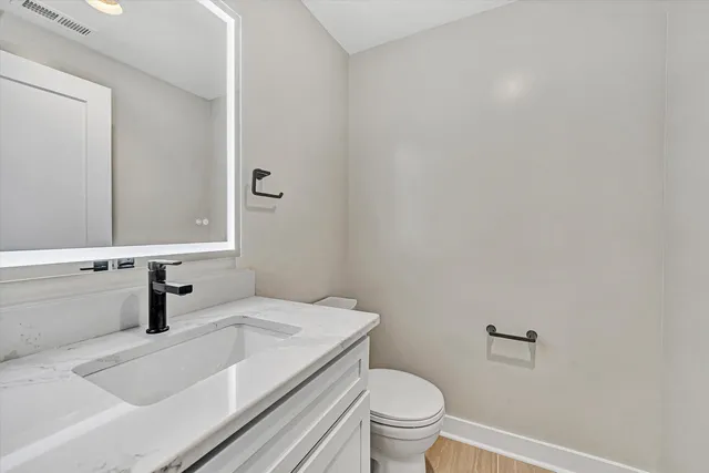 a bathroom with a granite countertop sink a toilet and a mirror