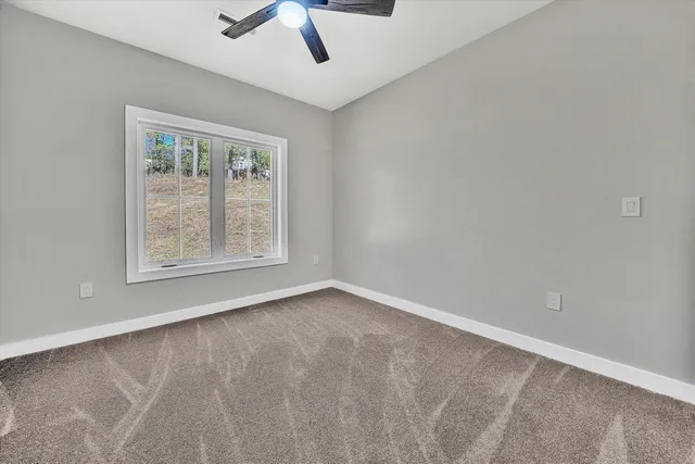 an empty room with chandelier fan and windows