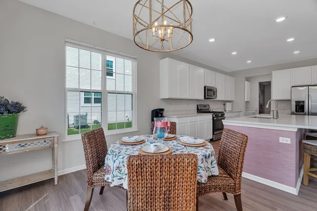 a kitchen with stainless steel appliances kitchen island granite countertop a dining table chairs refrigerator and sink