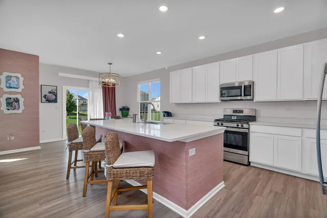 a kitchen with stainless steel appliances granite countertop a stove a sink dishwasher a microwave oven and a dining table with wooden floor