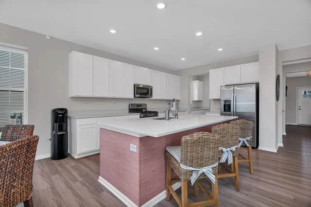 a kitchen with stainless steel appliances granite countertop a table chairs refrigerator and microwave