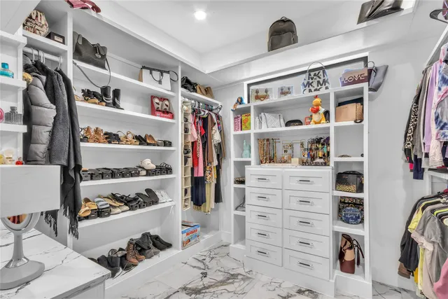 a view of walk in closet with clothes and shoes
