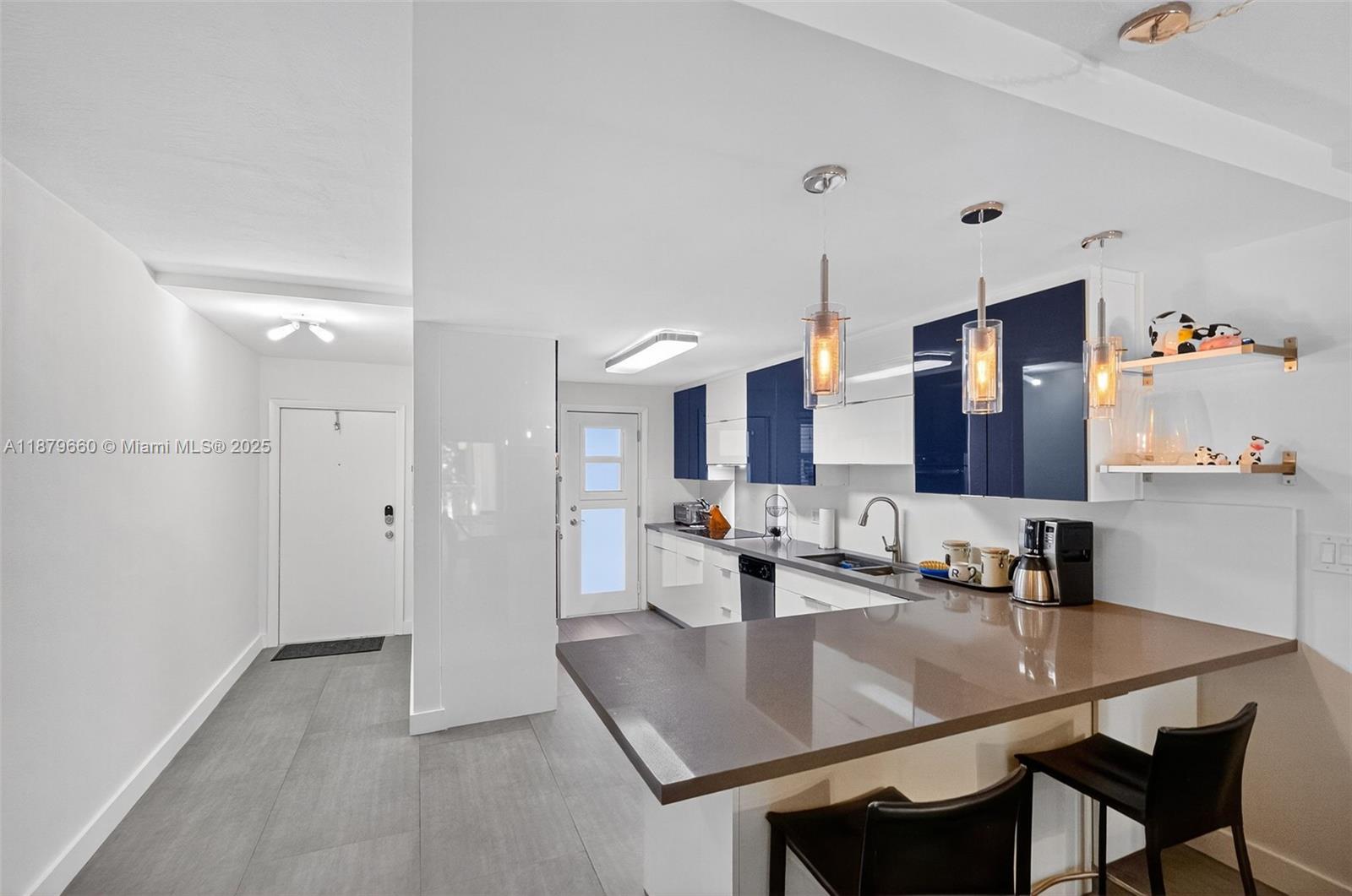240 Galen Drive, Unit 207 Key Biscayne, FL 33149 - Photo 7 of 21 a kitchen with a table chairs and a refrigerator