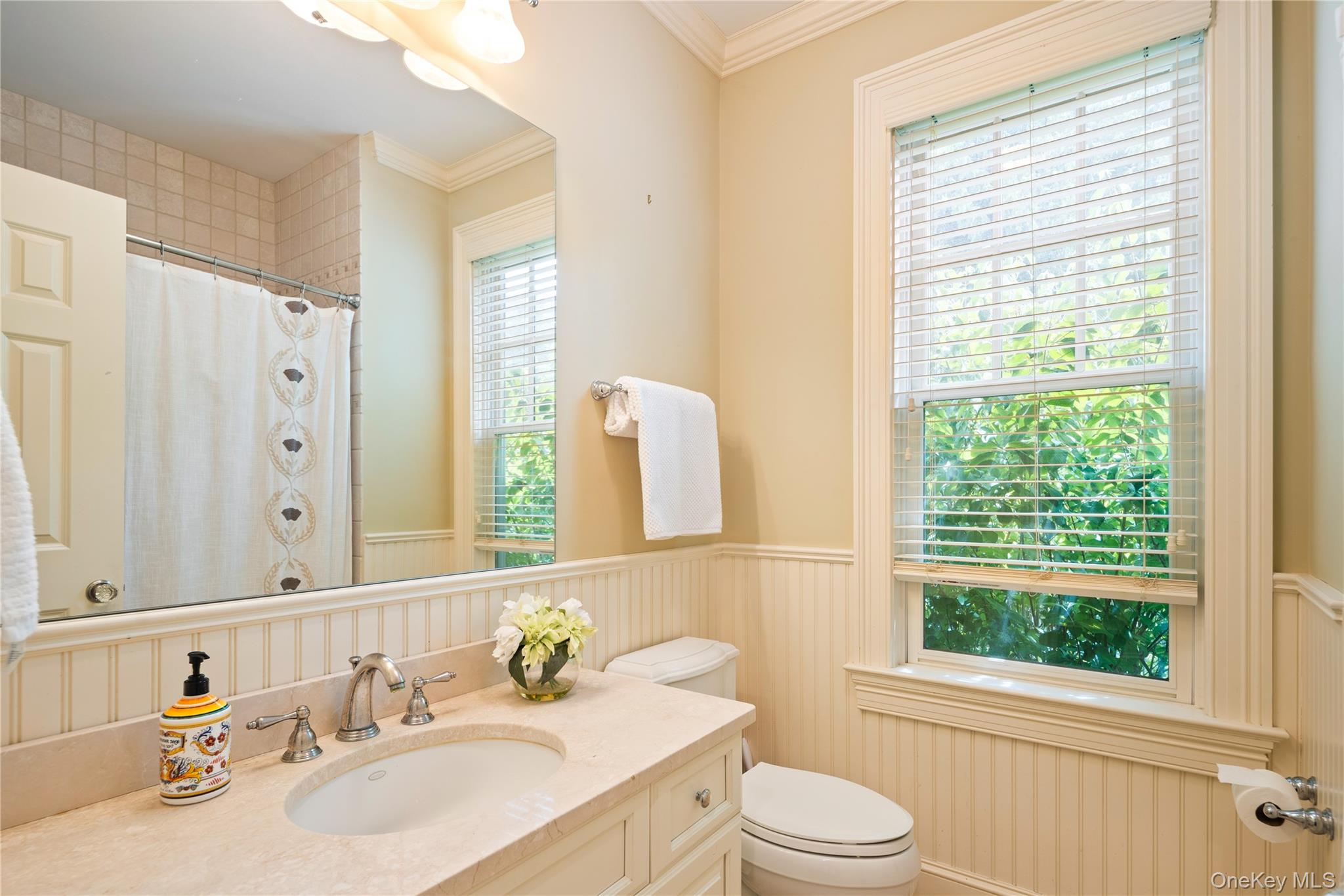 77 Byram Ridge Road Armonk, NY 10504 - Photo 26 of 48 Main floor full bath next to 5th bedroom with beadboard wainscot, storage vanity with undermount sink, crown molding, wall sconce, full tub/shower combo, Kohler fixtures