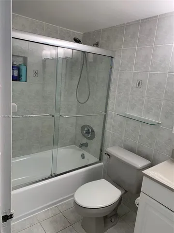 a view of a hallway with wooden floor and a bathroom