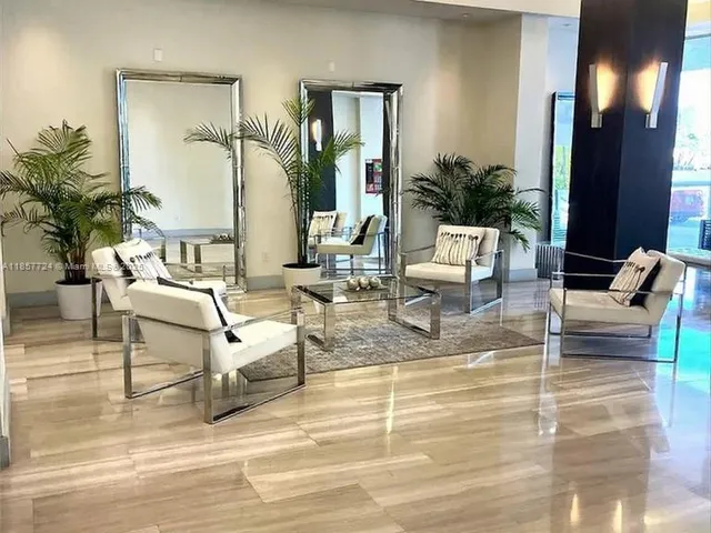 a view of a living room with a white wall and has a painting on the wall