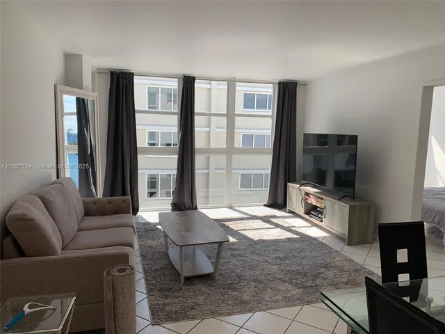 a living room with a bed furniture and a flat screen tv