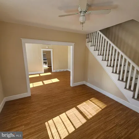 a view of an empty room with wooden floor and a rug