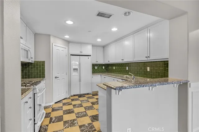 a kitchen with stainless steel appliances granite countertop a refrigerator and a sink