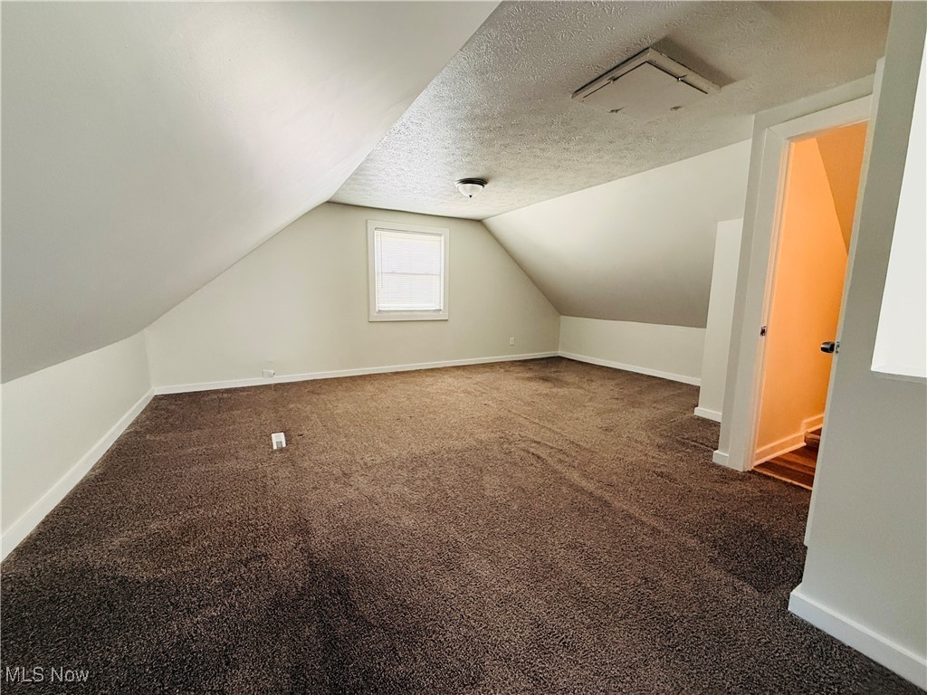 5239 Arch Street Maple Heights, OH 44137 - Photo 12 of 25 Bonus room featuring dark colored carpet, a textured ceiling, and lofted ceiling