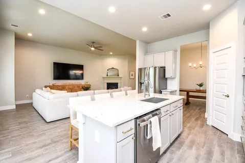 a large white kitchen with a stove a sink dishwasher and a refrigerator with wooden floor