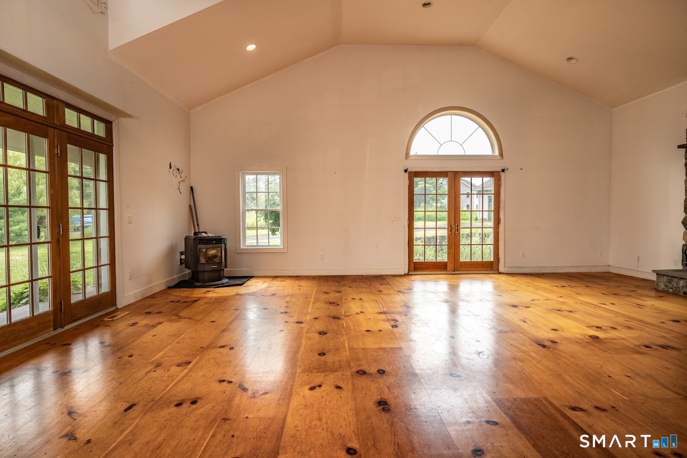 19 High Street Middlefield, CT 06455 - Photo 5 of 18 Expansive great room with soaring vaulted ceilings, wide-plank pine floors, oversized windows, and French doors opening to the covered porch and grounds.