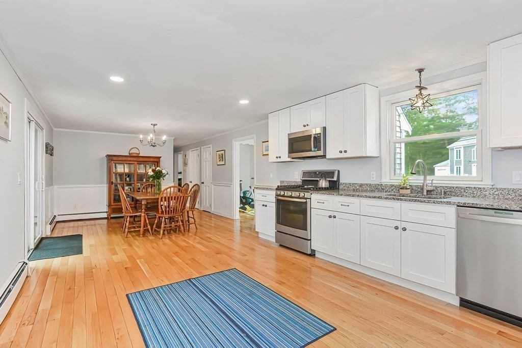 79 Emerson Way Barnstable, MA 02632 - Photo 11 of 29 a kitchen with stainless steel appliances granite countertop a stove top oven a sink dishwasher a dining table and chairs with wooden floor