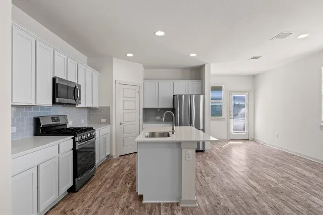 a kitchen with stainless steel appliances a refrigerator and a stove top oven