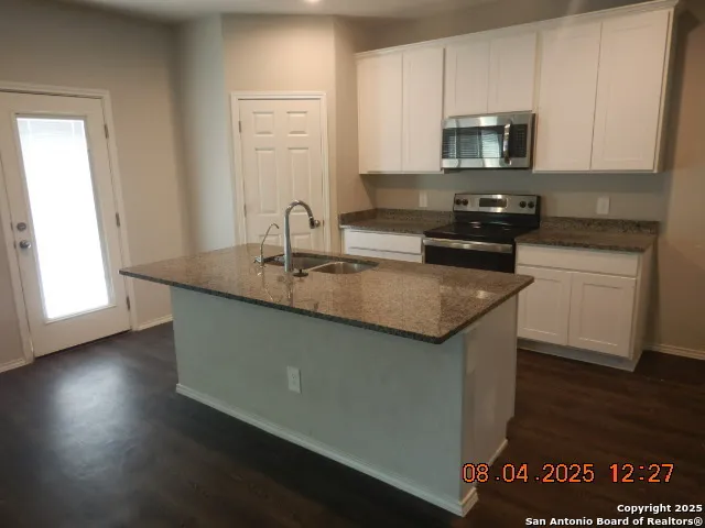 a kitchen with stainless steel appliances granite countertop a sink a stove a microwave and cabinets