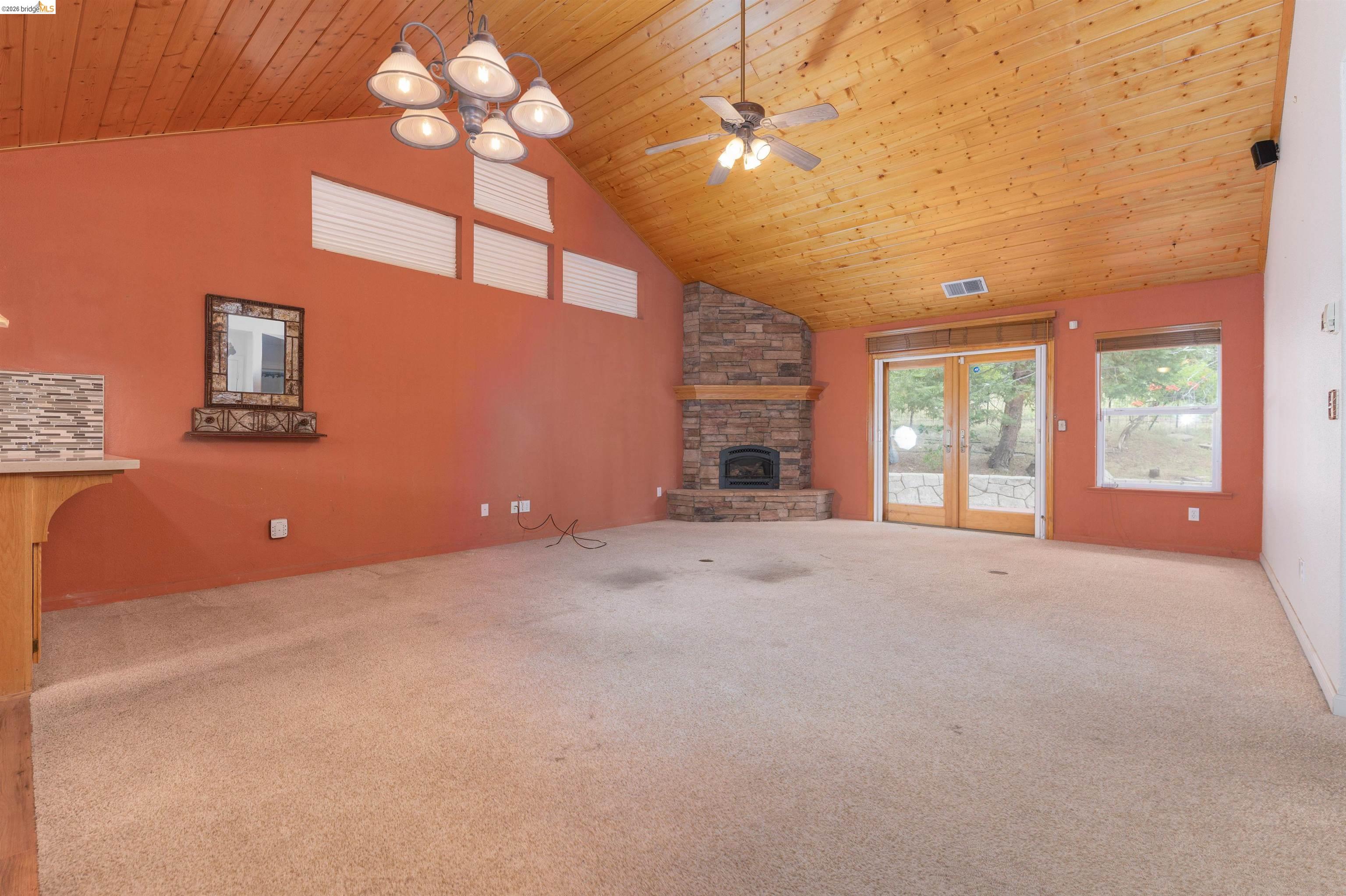 22401 Ridge Road Twain Harte, CA 95383 - Photo 10 of 56 Great room featuring a vaulted wood-finish ceiling, a stone-clad fireplace with hearth, a multi-light chandelier, a ceiling fan, and French doors
