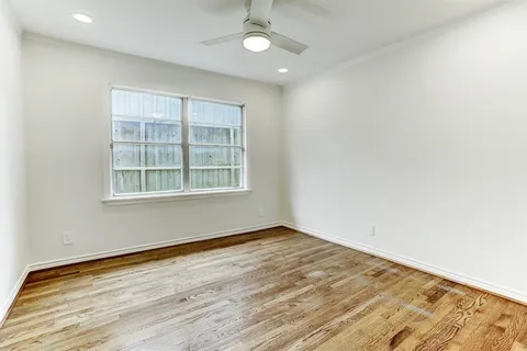 an empty room with wooden floor cabinet and windows