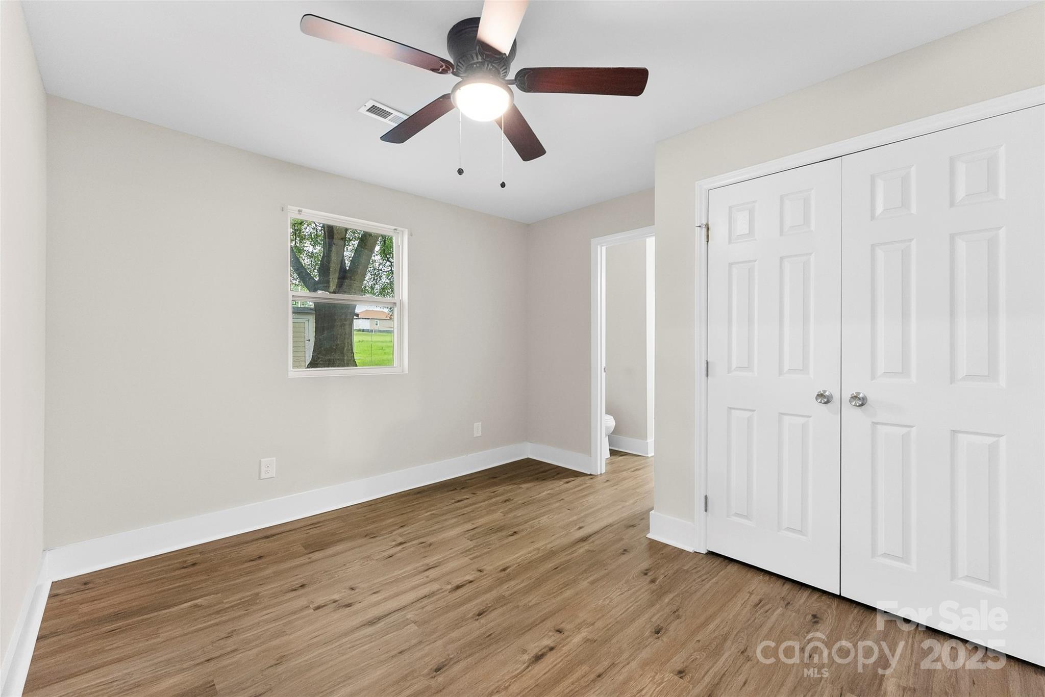 601 Rhyne Circle, Unit B Gastonia, NC 28054 - Photo 13 of 32 an empty room with wooden floor ceiling fan and windows