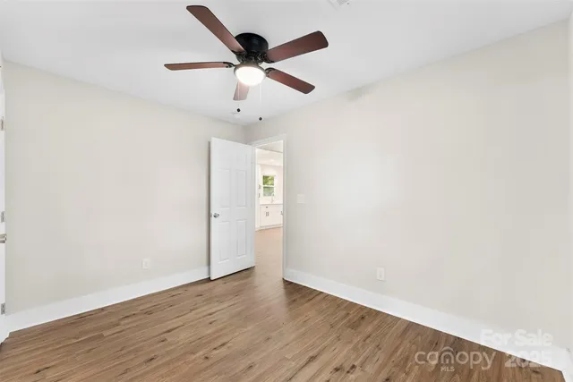 an empty room with wooden floor and ceiling fan