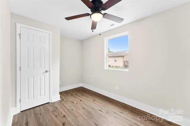 an empty room with wooden floor a ceiling fan and a ceiling fan