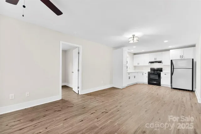 a view of a kitchen with a sink stove cabinets and empty room