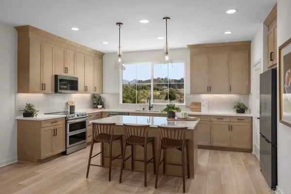 a kitchen with kitchen island granite countertop a sink a stove a refrigerator cabinets and wooden floor