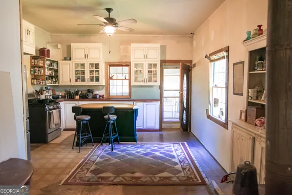 a view of a kitchen with stainless steel appliances granite countertop a stove a refrigerator a dining table and chairs with wooden floor