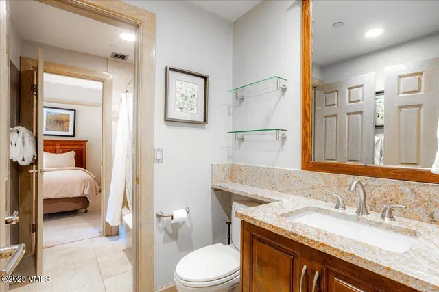 a bathroom with a granite countertop sink a toilet and a mirror
