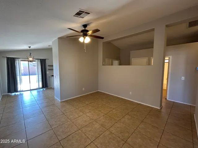 a view of an empty room with window and chandelier fan