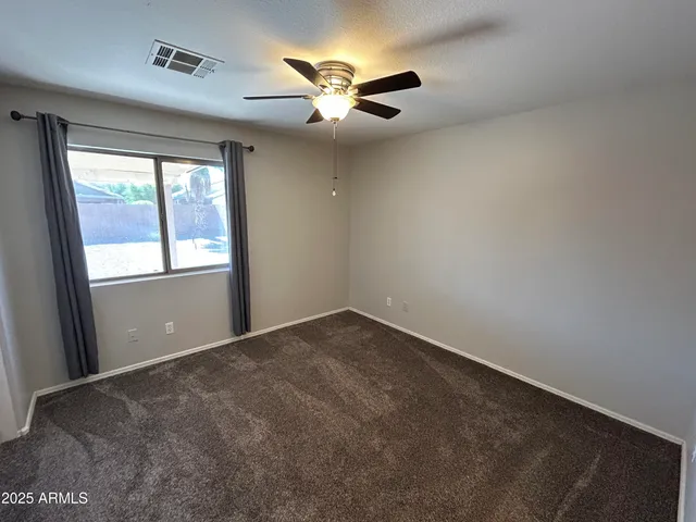 an empty room with windows and ceiling fan