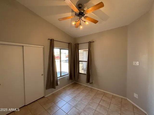 a view of an empty room with window and chandelier fan