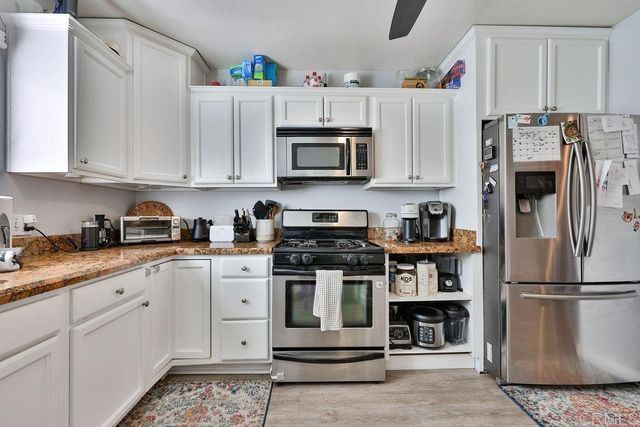 a kitchen with stainless steel appliances granite countertop a refrigerator a stove and white cabinets