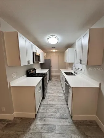 a large kitchen with stainless steel appliances kitchen island granite countertop a stove a sink dishwasher and a refrigerator with wooden floor
