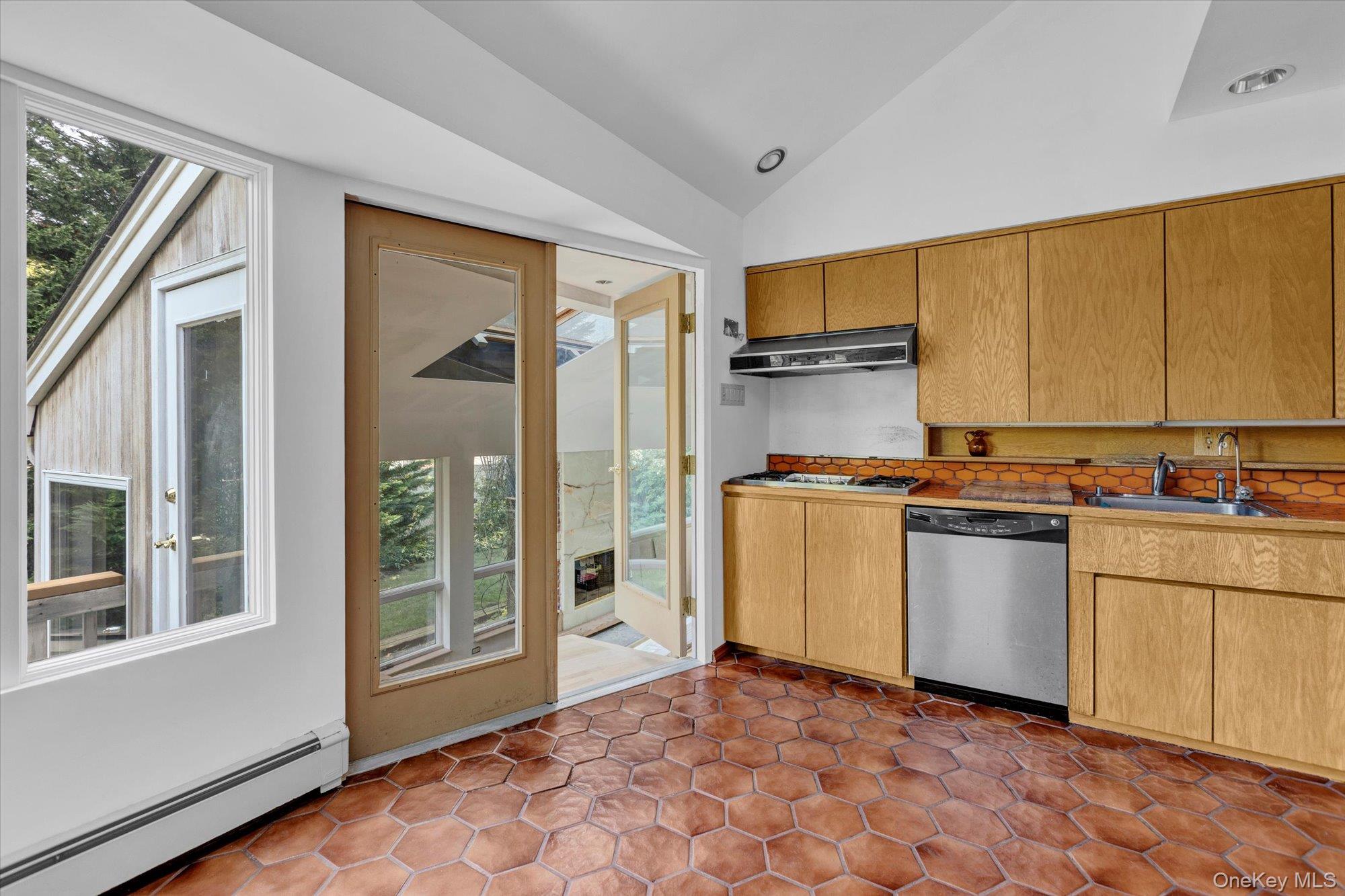 19 Clearland Road Syosset, NY 11791 - Photo 11 of 22 Kitchen featuring a baseboard heating unit, lofted ceiling, stainless steel dishwasher, a skylight, and under cabinet range hood
