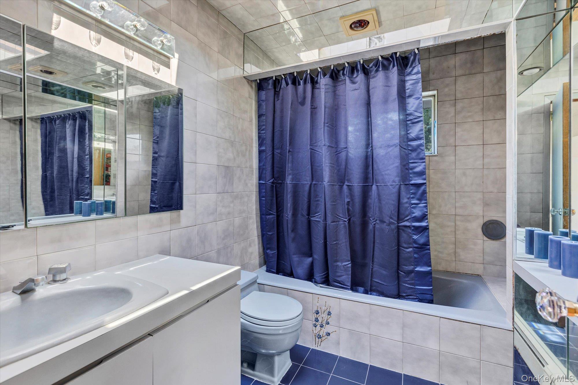 19 Clearland Road Syosset, NY 11791 - Photo 19 of 22 Full bathroom with tile walls, tiled shower / bath, vanity, and dark tile patterned floors