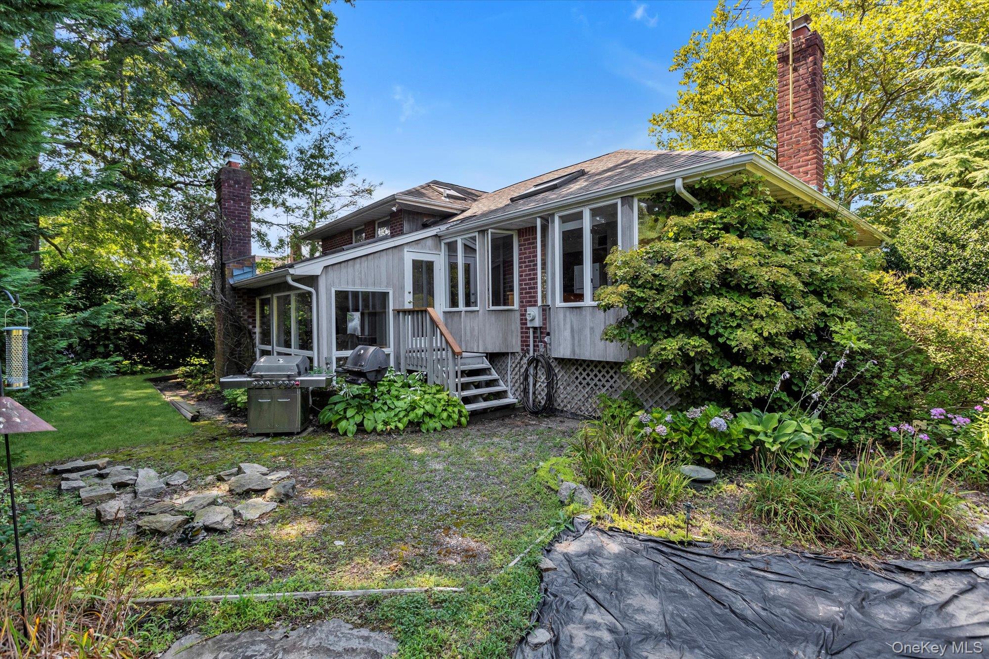 19 Clearland Road Syosset, NY 11791 - Photo 20 of 22 View of home's exterior featuring a chimney, a lawn, stairs, and a sunroom