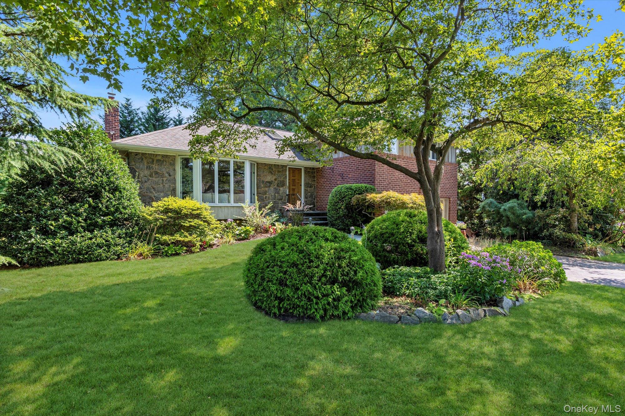 19 Clearland Road Syosset, NY 11791 - Photo 3 of 22 View of front of house featuring stone siding, a front yard, and a chimney