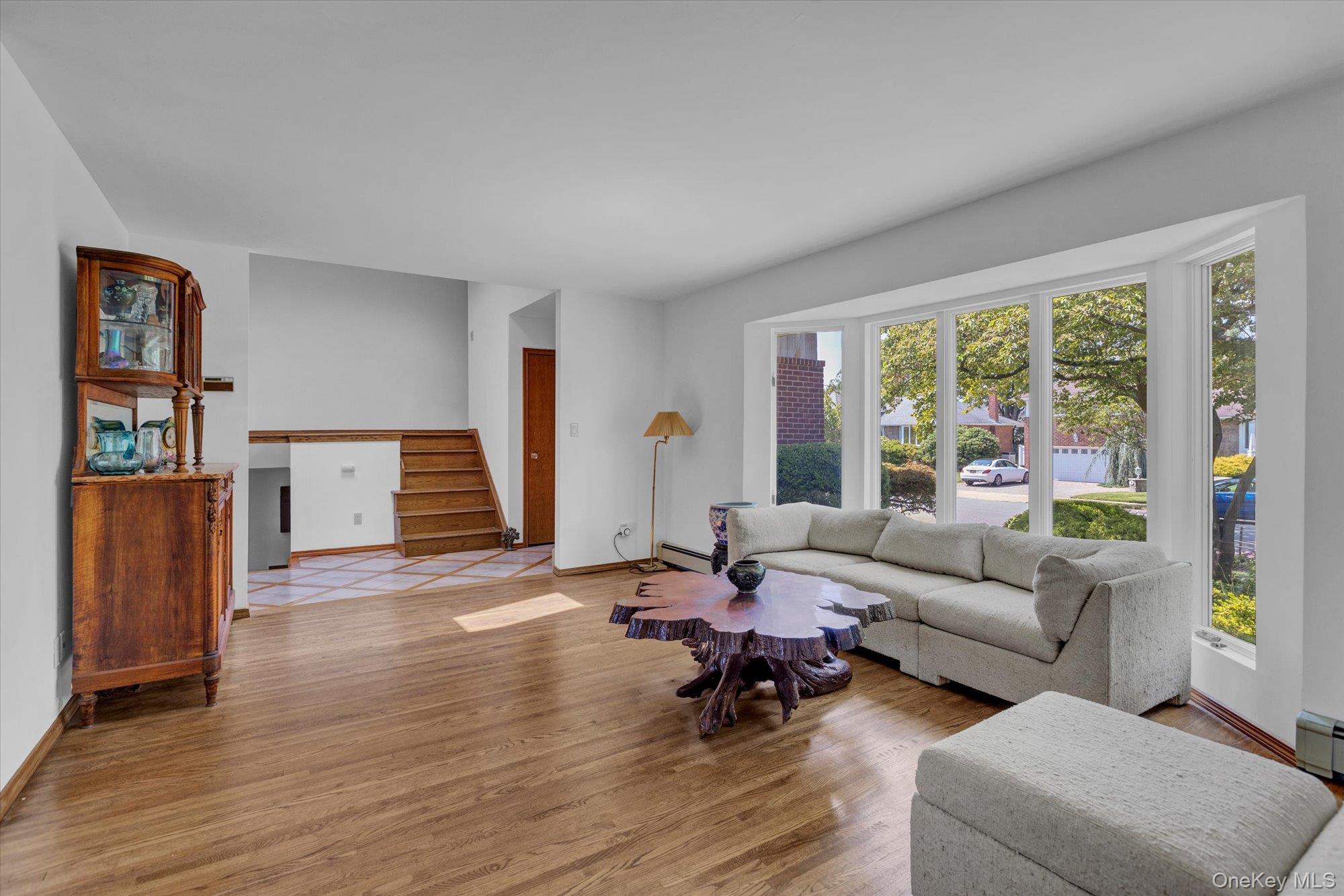 19 Clearland Road Syosset, NY 11791 - Photo 5 of 22 Living room featuring wood finished floors, stairs, and a baseboard radiator