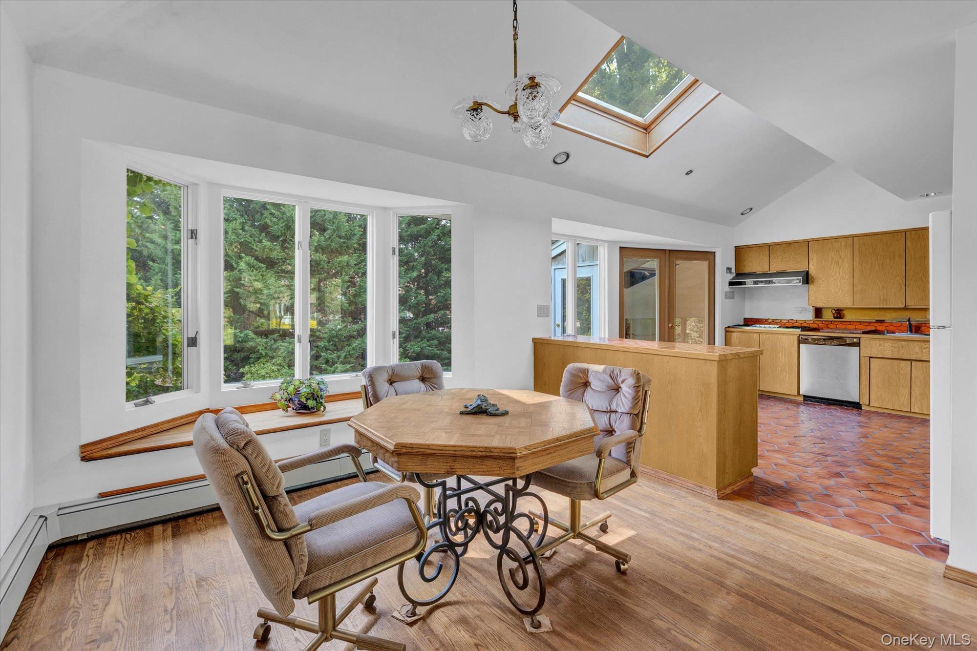 19 Clearland Road Syosset, NY 11791 - Photo 8 of 22 Dining room with a skylight, light wood finished floors, a chandelier, high vaulted ceiling, and a baseboard heating unit