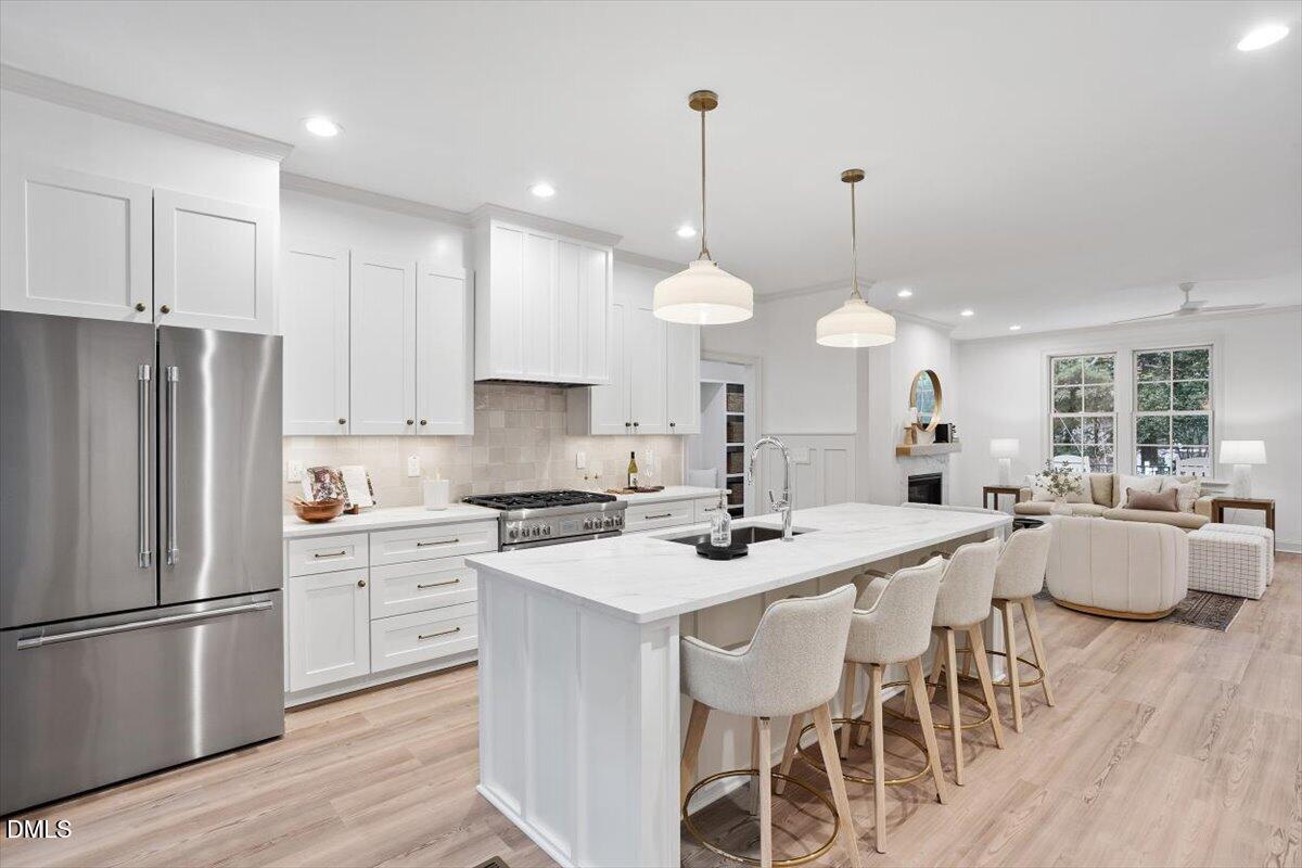 203 Baggett Avenue Raleigh, NC 27604 - Photo 12 of 51 a kitchen with stainless steel appliances a stove a sink a refrigerator a dining table and chairs with wooden floor