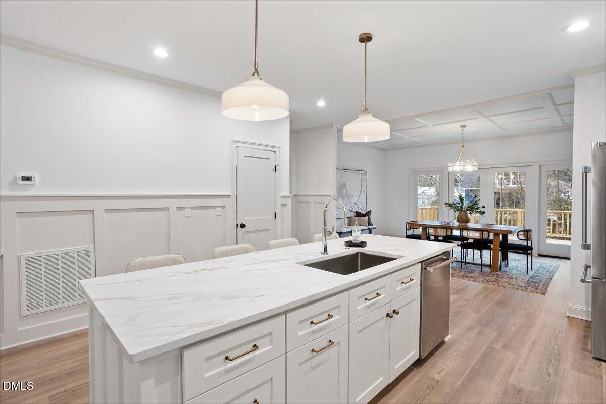 203 Baggett Avenue Raleigh, NC 27604 - Photo 18 of 51 a kitchen with stove a sink and white cabinets with wooden floor