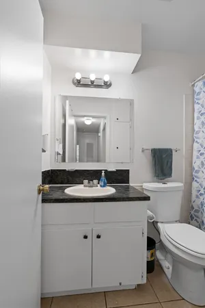 a bathroom with a granite countertop sink a toilet and mirror
