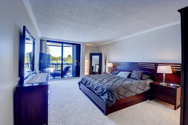 a bedroom with a large bed and a flat tv screen on dresser