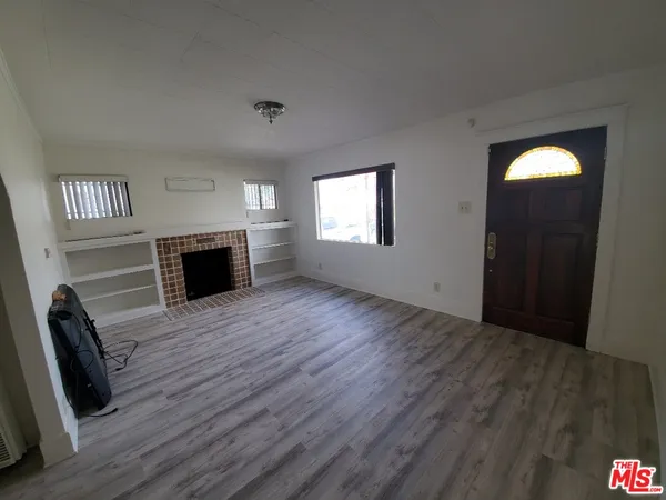 an empty room with wooden floor a fireplace and windows