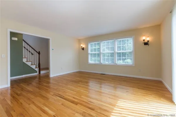 a view of an empty room with wooden floor and a window