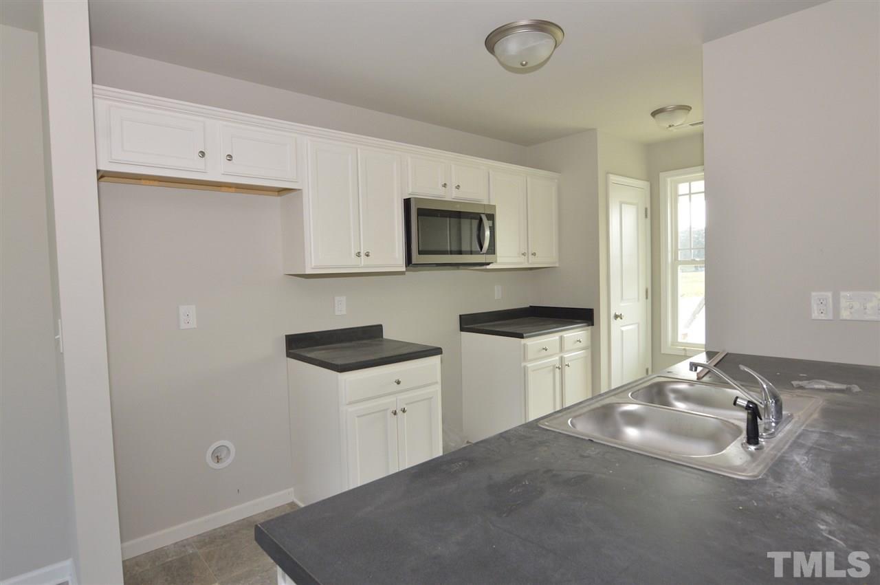 92 Willow Ridge Circle Willow Spring, NC 27592 - Photo 7 of 16 a kitchen with granite countertop a sink a stove top oven and white cabinets