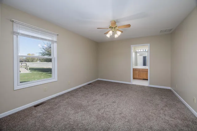 an empty room with windows and ceiling fan