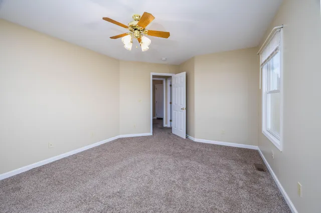 an empty room with a ceiling fan and a window