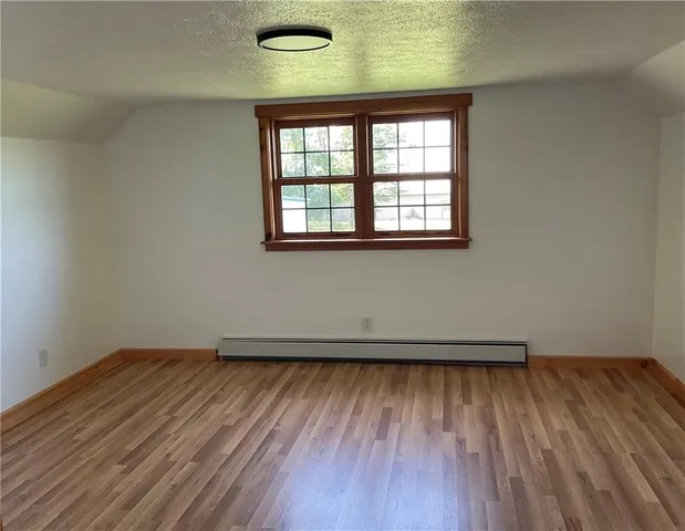 a view of an empty room with wooden floor and windows