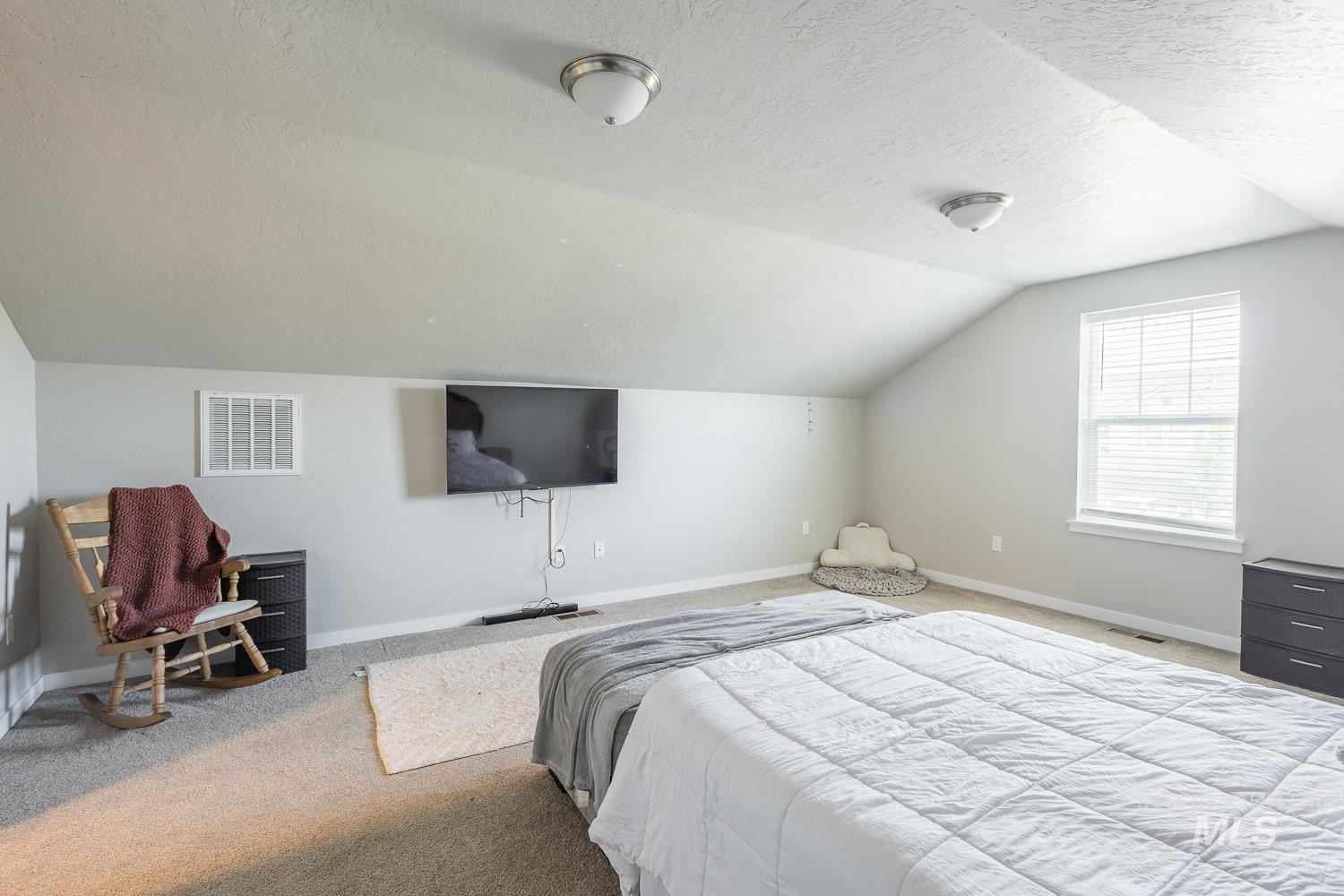 12623 Shadow Peak Street Caldwell, ID 83607 - Photo 45 of 50 Spacious room featuring sloped ceilings, a large window with blinds, wall-mounted television, and flush-mount ceiling lights